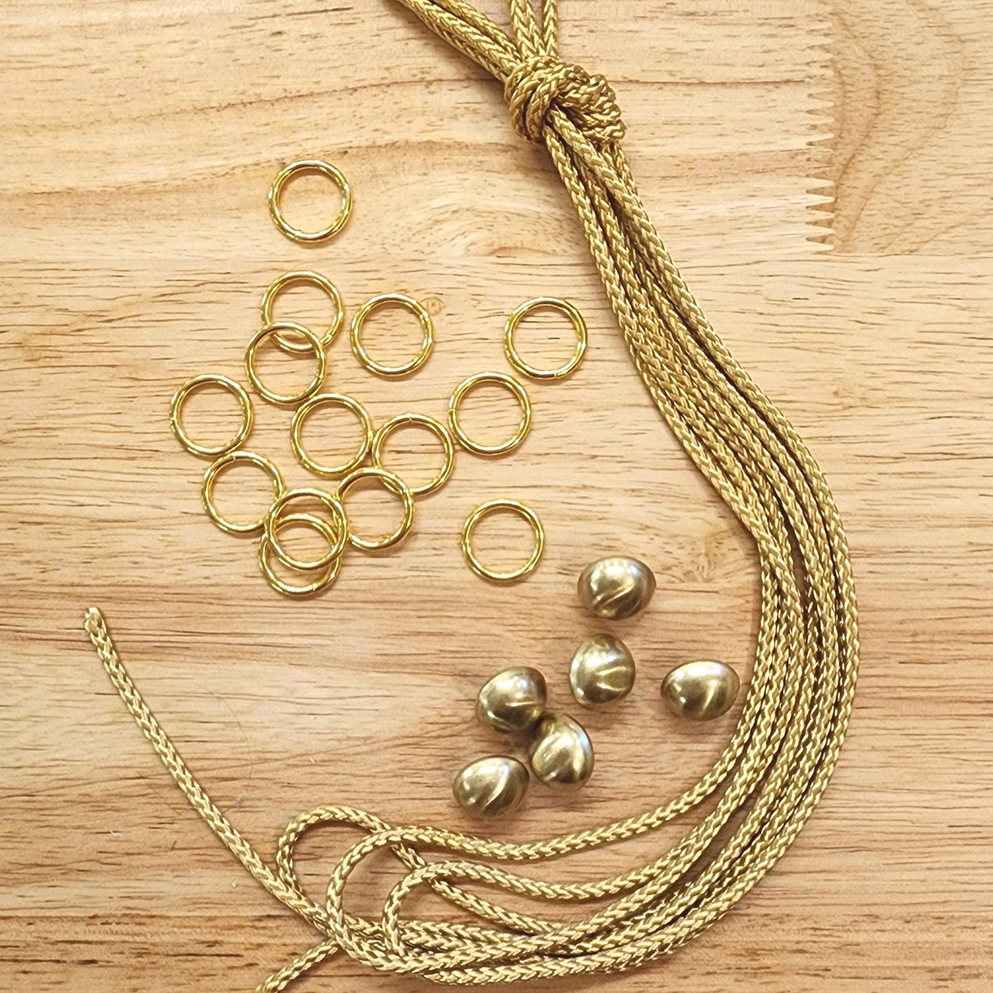 Gold jewelry components including chains and rings on a wooden surface