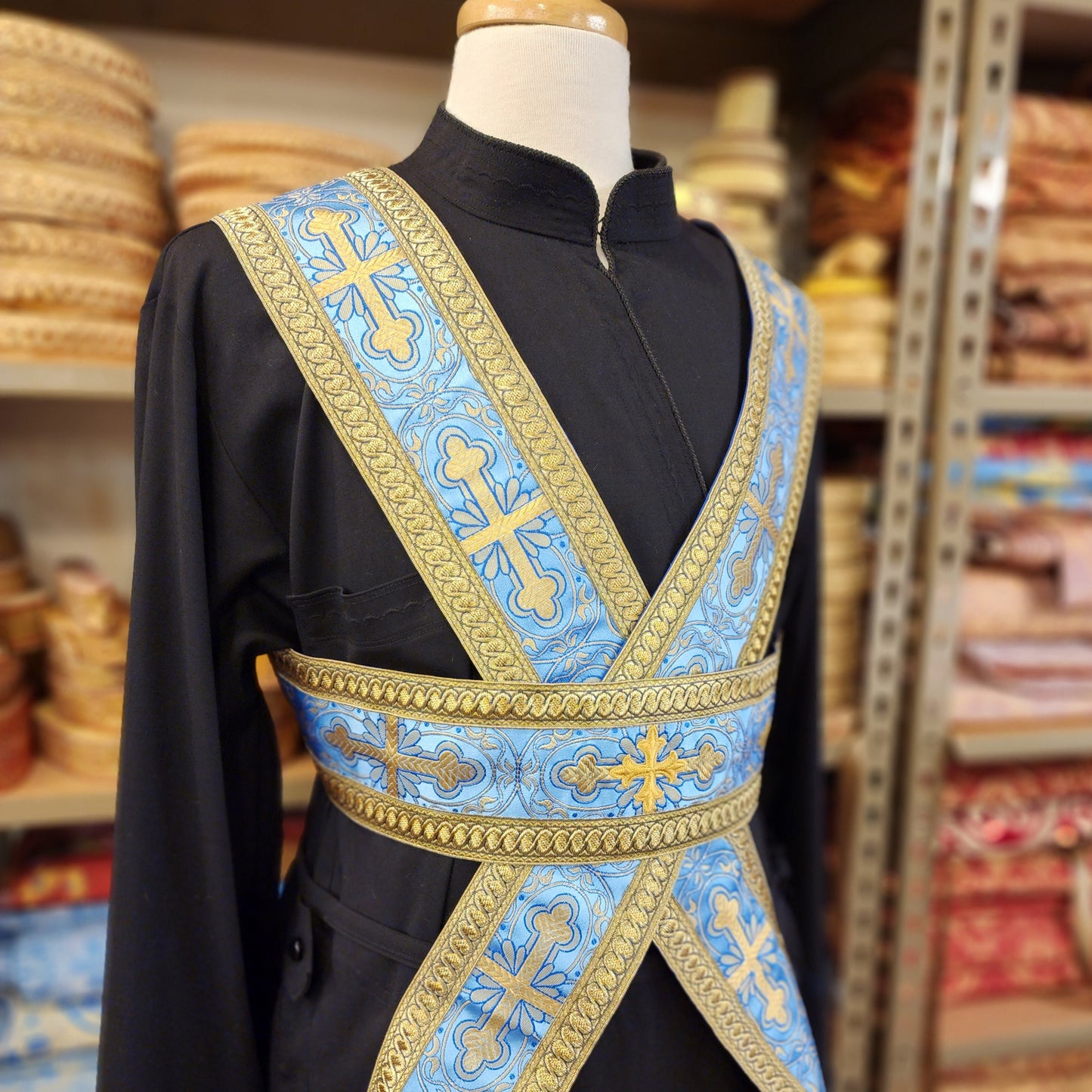 Black robe with blue and gold embroidered vestment on a mannequin in a store setting.