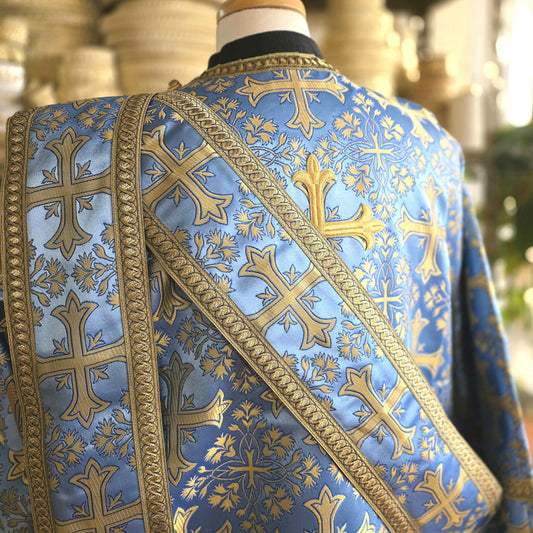 Blue liturgical vestment with gold crosses and patterns on a blurred background