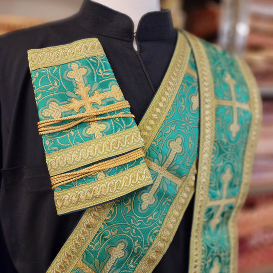 Decorative liturgical vestment with green and gold embroidery on a blurred background