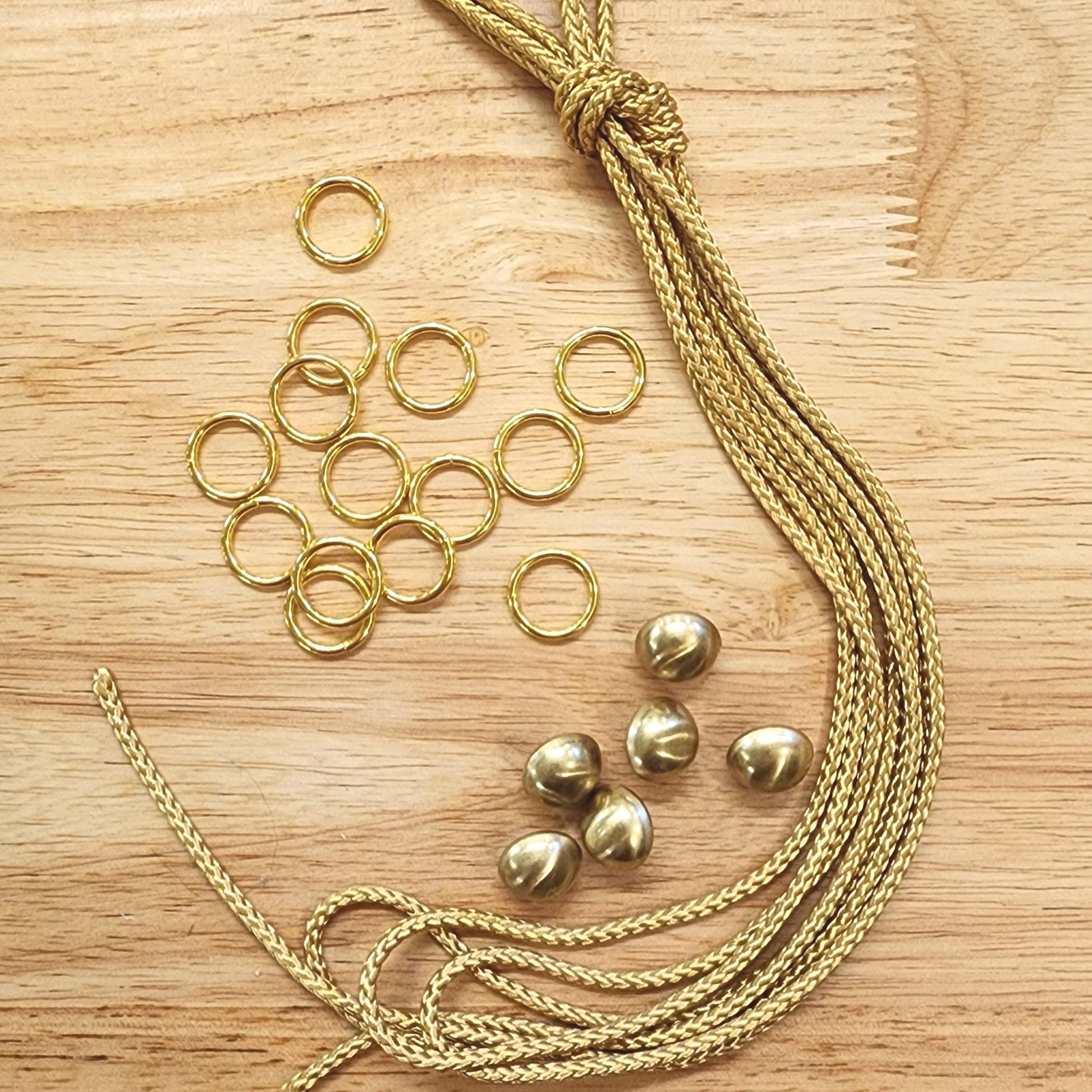 Gold jewelry components including chains and rings on a wooden surface